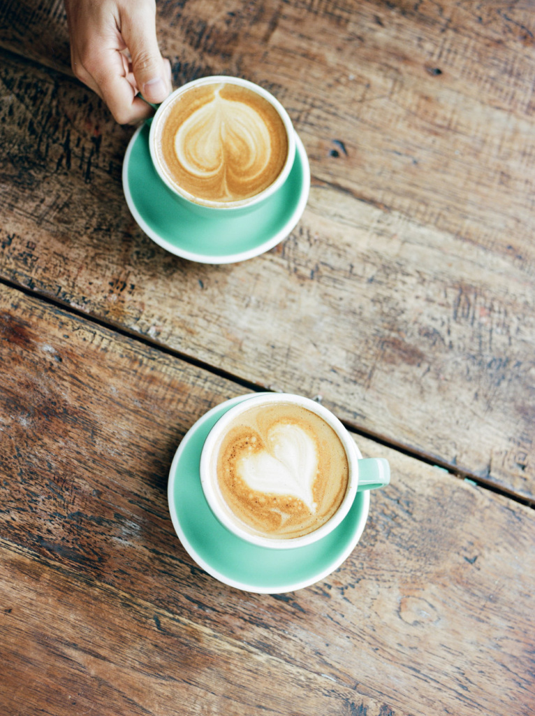 Two cups of coffee on a wooden table.