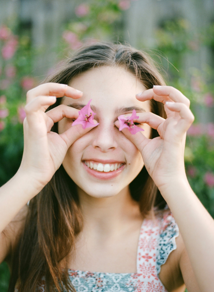 A girl with pink flowers in a family photography shoot.