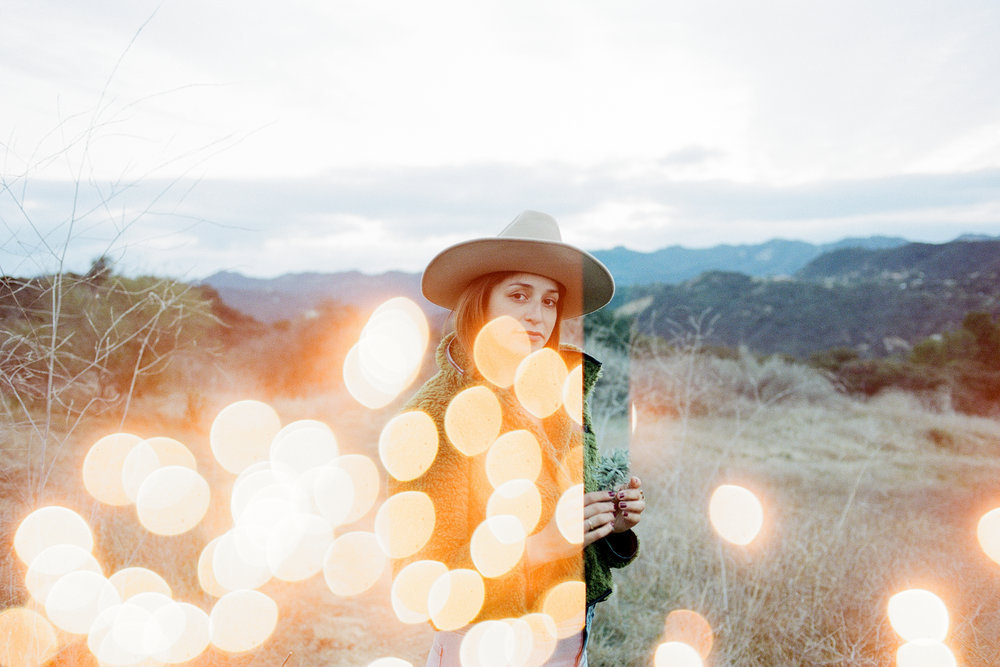 A woman in a hat standing in a field with lights.