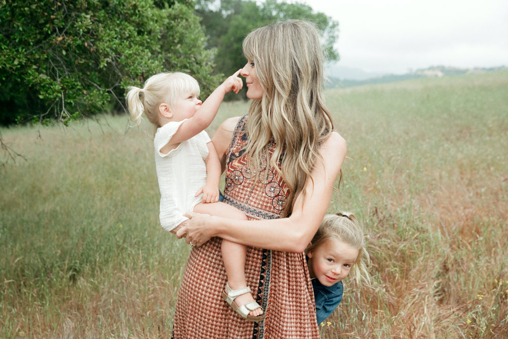 mother with two young daughter in nature playfully interacting