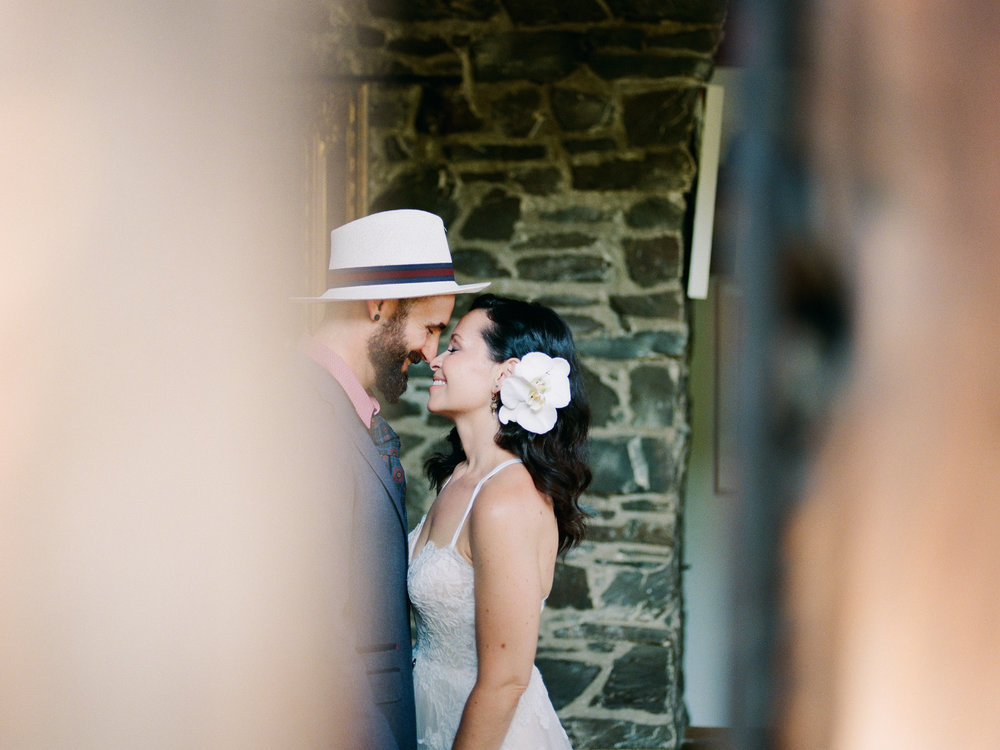 A bride and groom share a kiss in a stone archway.