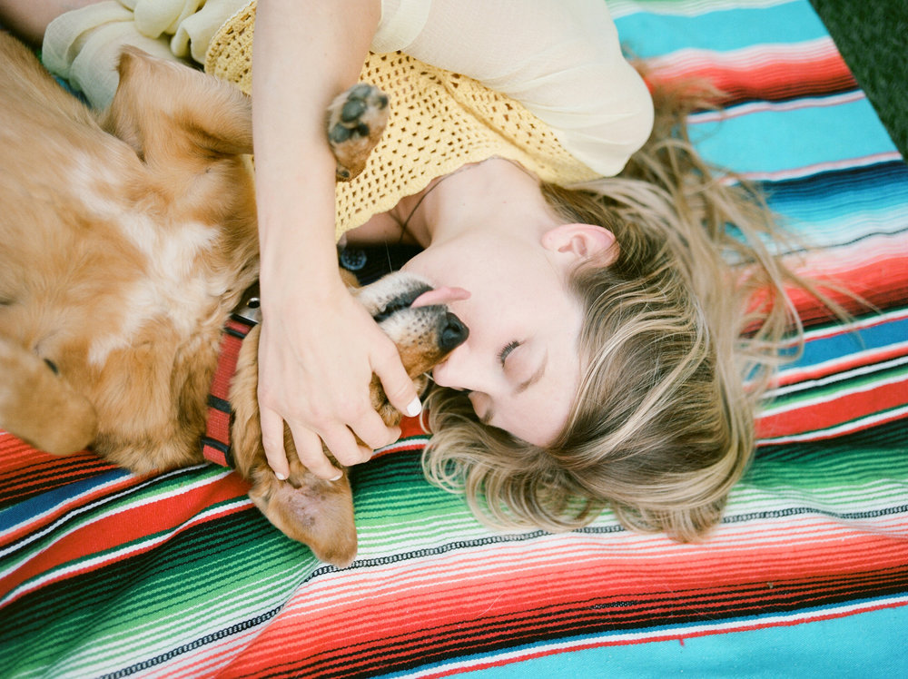 A woman laying on a blanket with a dog.