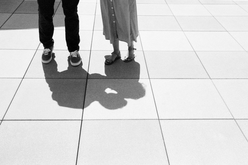 A black and white photo of a couple standing on a tile floor.