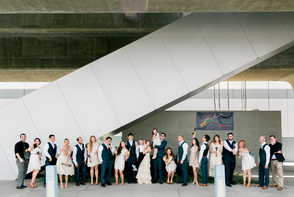 A wedding party posing in front of a bridge.