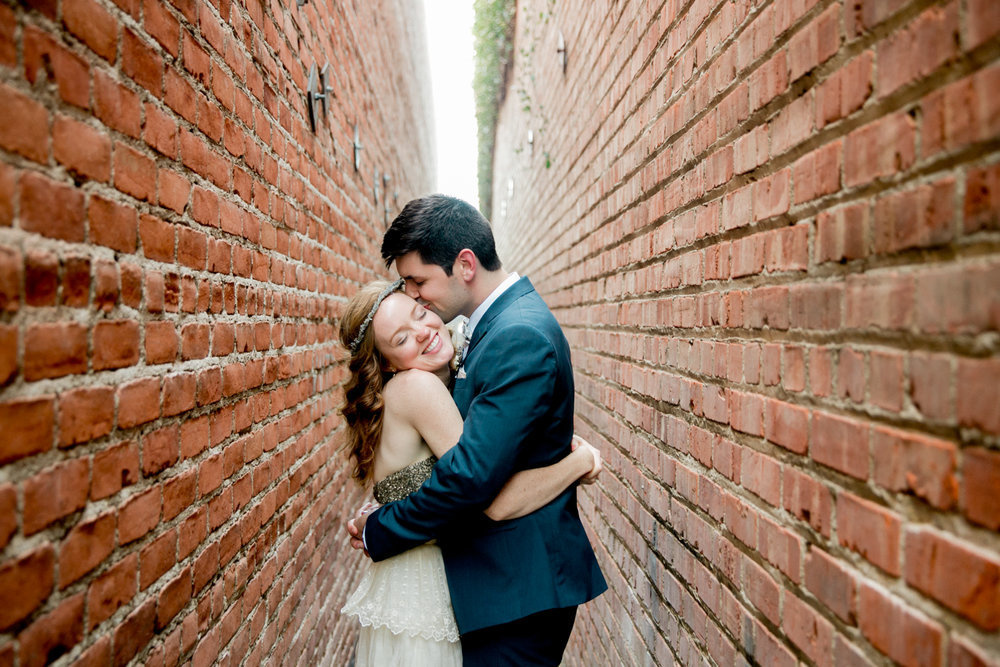 A bride and groom hugging in an alleyway.
