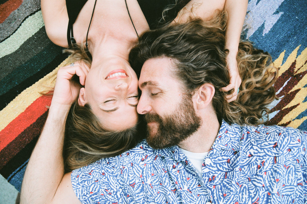 A man and woman laying on a colorful rug.