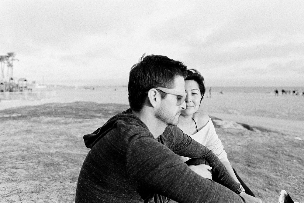 A black and white photo of a man and woman sitting on the beach.