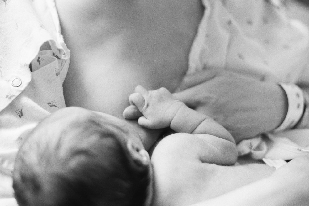 nursing newborn holding mothers finger