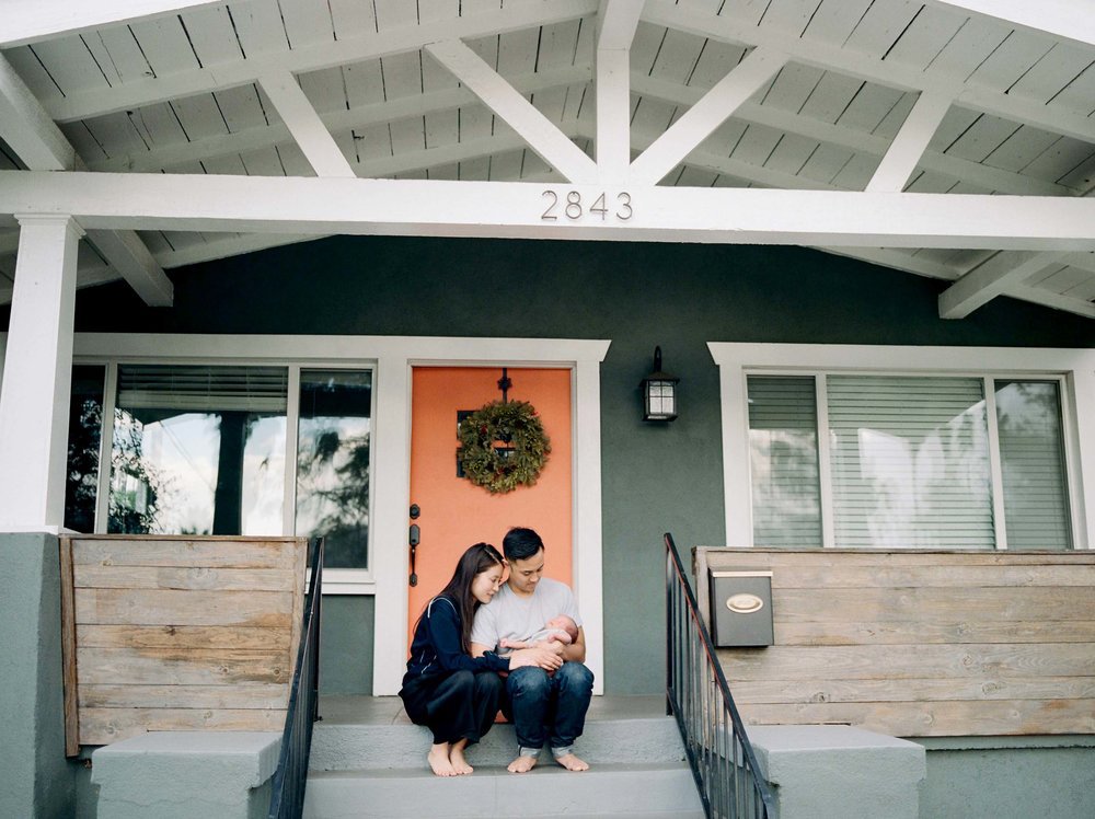 parents sitting on front porch holding newborn