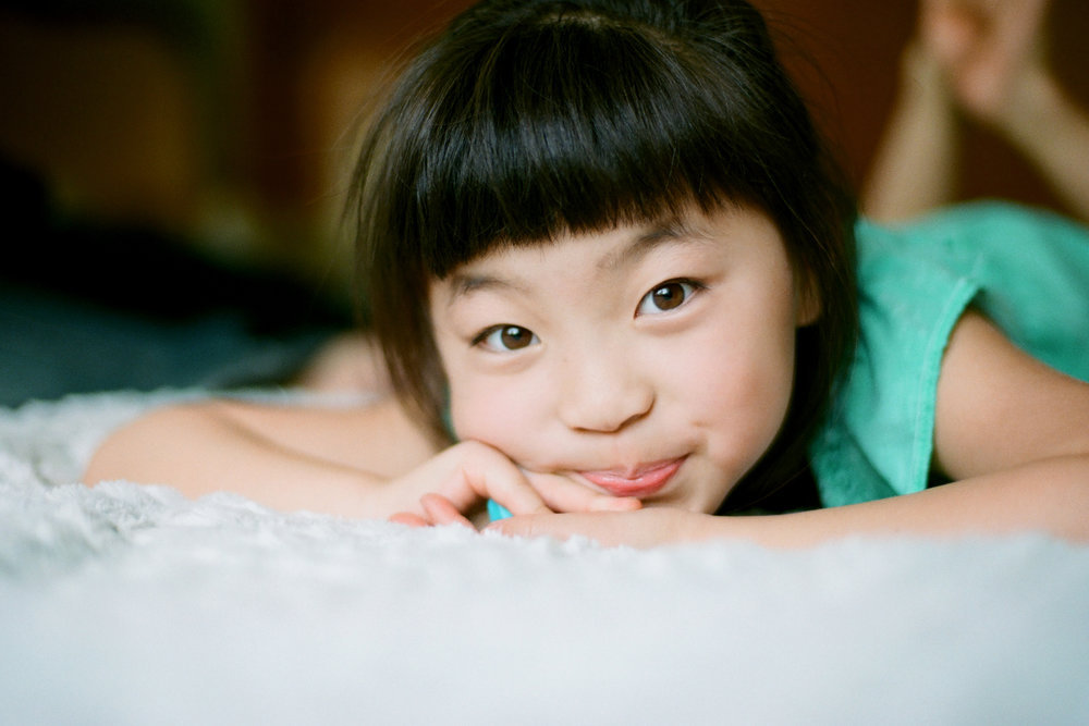 portrait of young girl laying on bed and smiling at camera