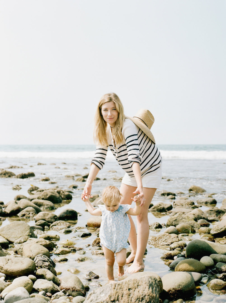 mother and young girl at the beach holding hands in a tide pool