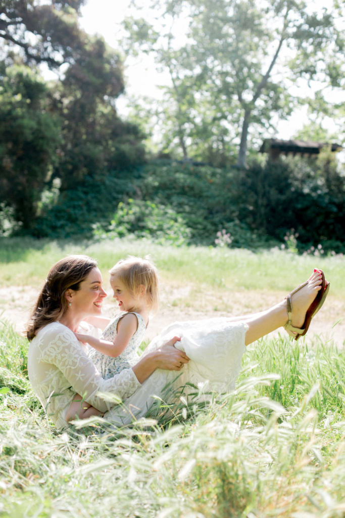 mother and young daughter playfully sitting in the grass and interacting