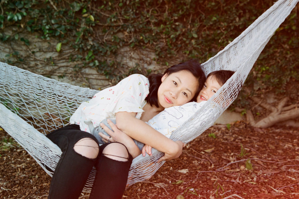 A woman laying in a hammock with her baby.