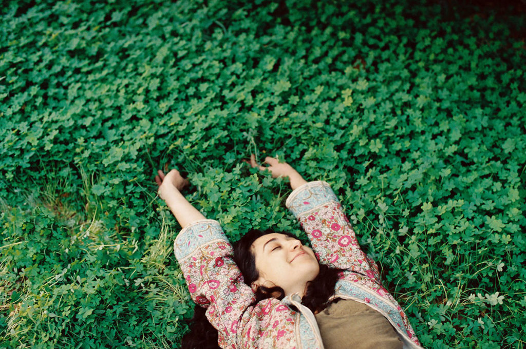 young woman laying in clovers and stretching playfully