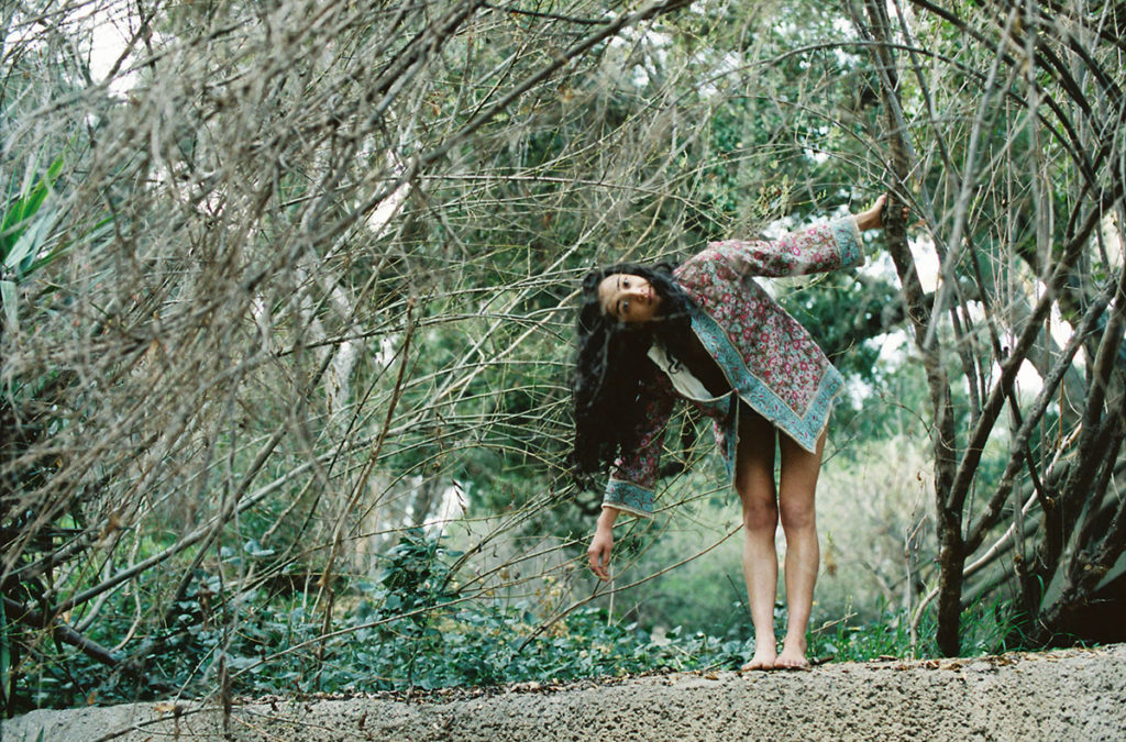 woman in nature tipping to the side childlike