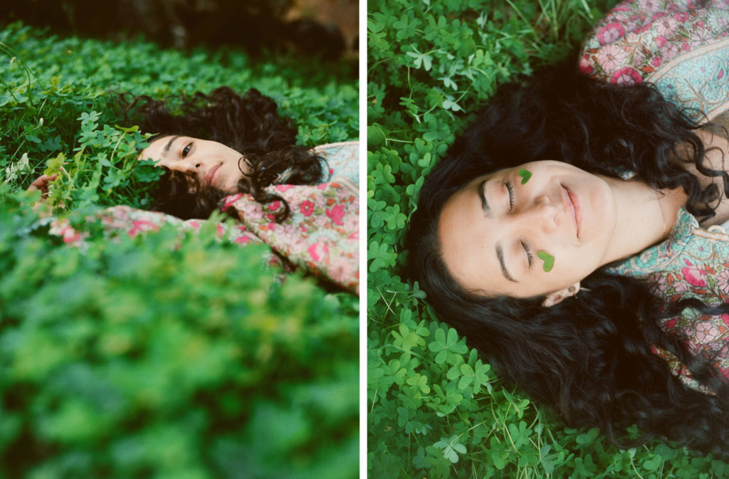 young woman laying in clovers happily