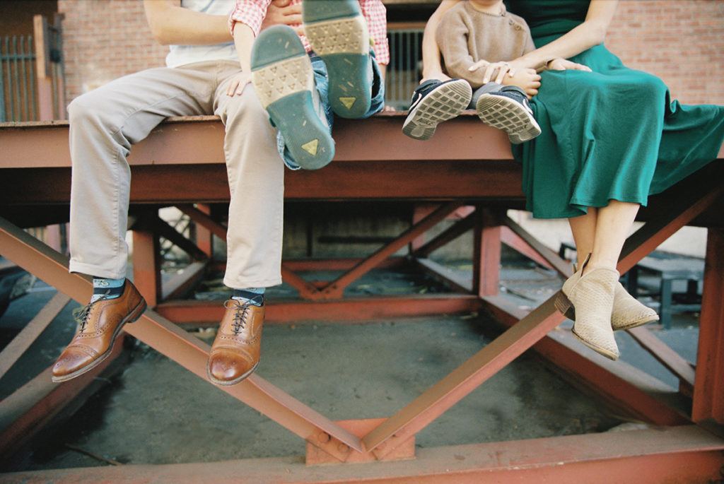 Family of 4 sitting on a metal dock with focus on feet