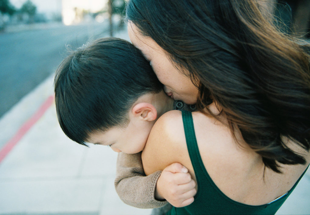 close up of mother kissing yound sons neck 