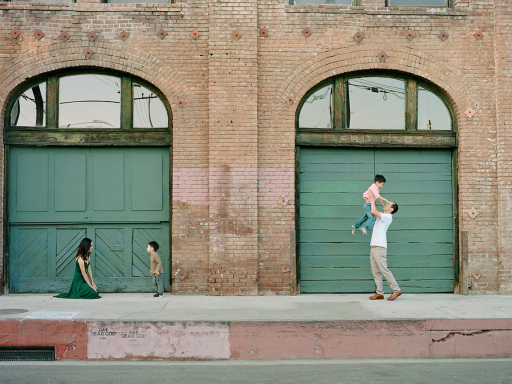 family of four with brick wall background, parents playing and interacting with kids