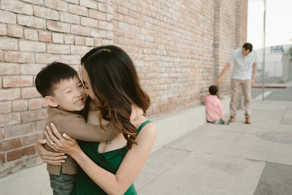 mom nuzzling young son while dad and other son talk in the background