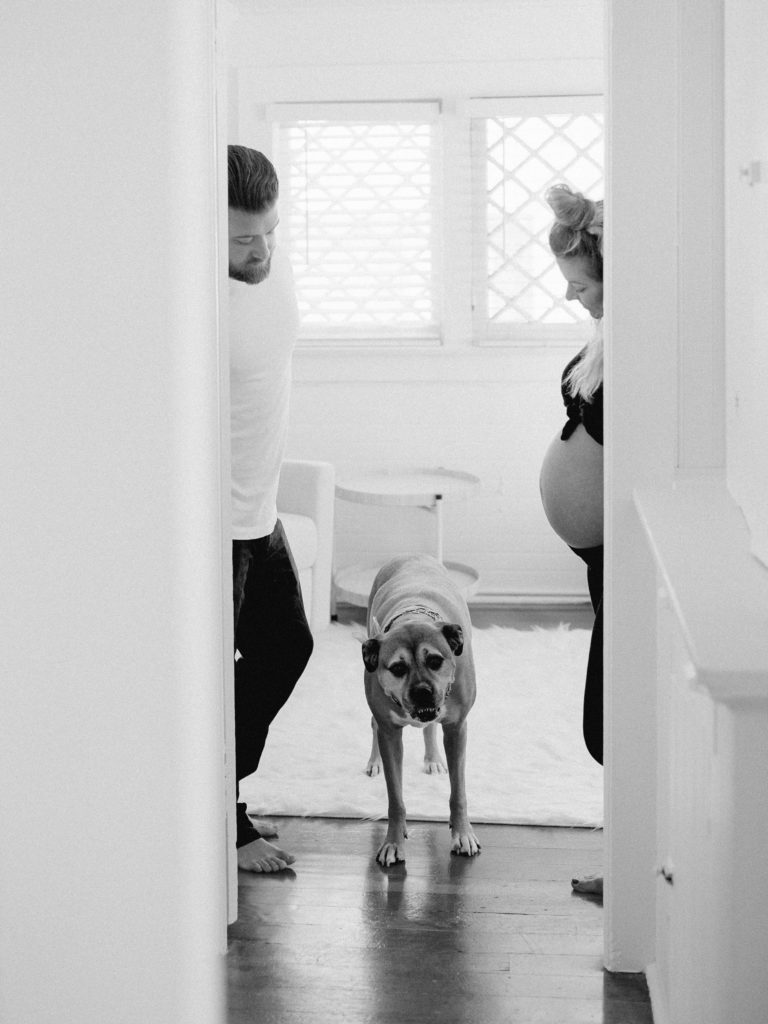 A family, including a man and woman, captured in a hallway with their beloved dog in a family photography session.
