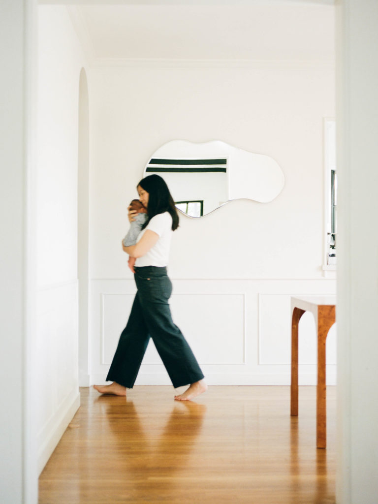 A family portrait capturing a woman strolling with an infant through a hallway.