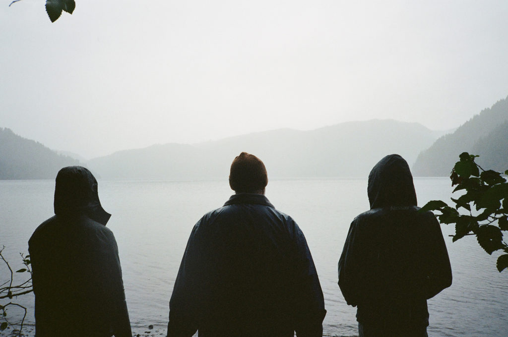 Three people standing by a body of water.