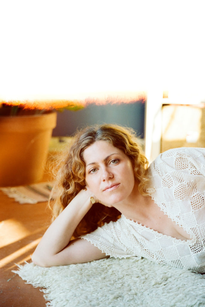 A woman in a white dress laying on a rug.