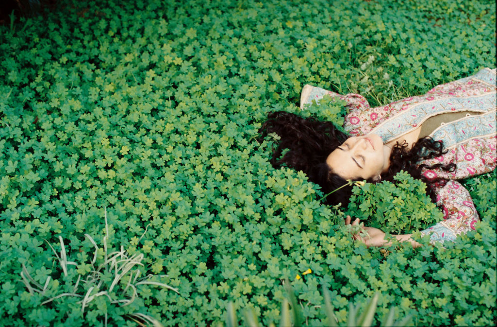 A woman laying in a field of green plants.