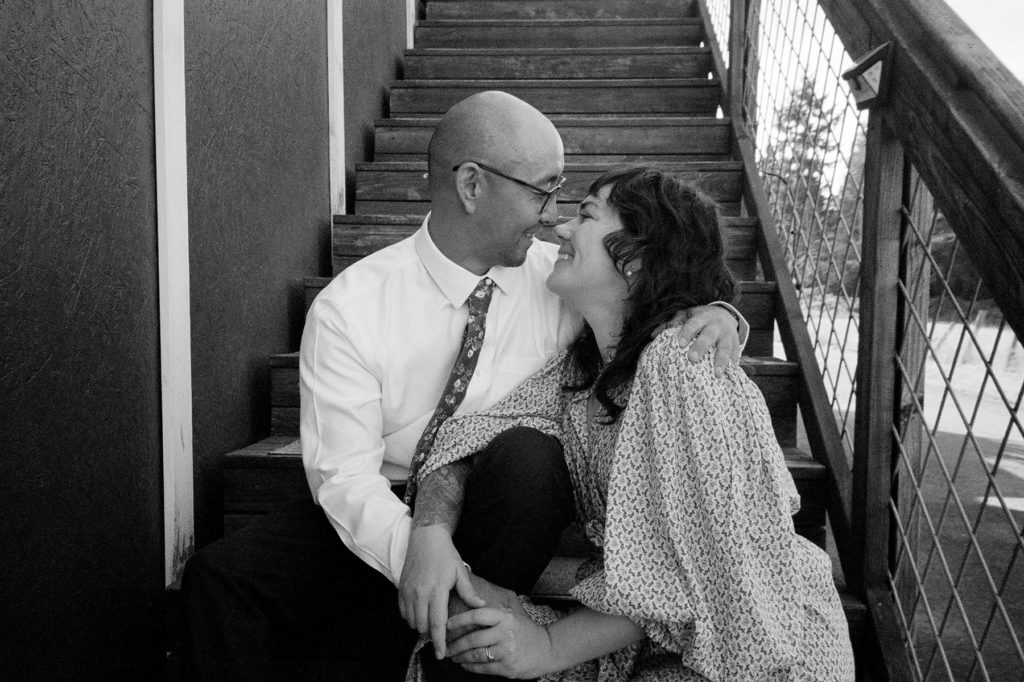 A black and white photo of a man and woman sitting on stairs.