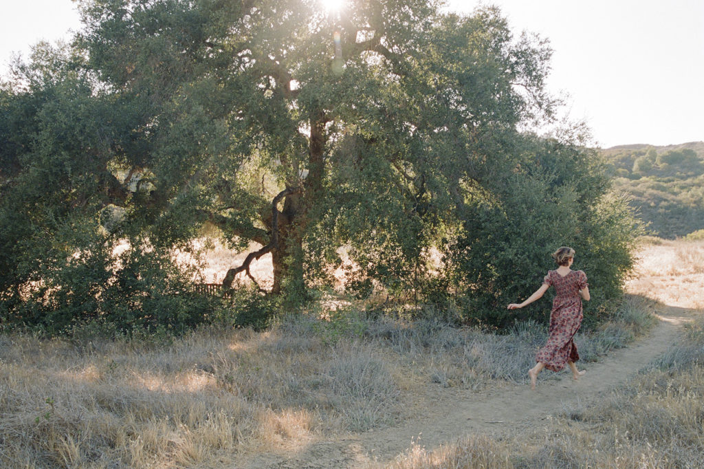 A woman in a dress walking through a field.