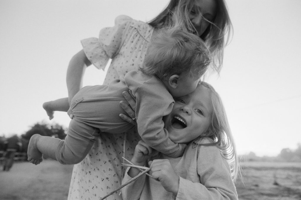 A black and white family photography capturing a woman holding two children.