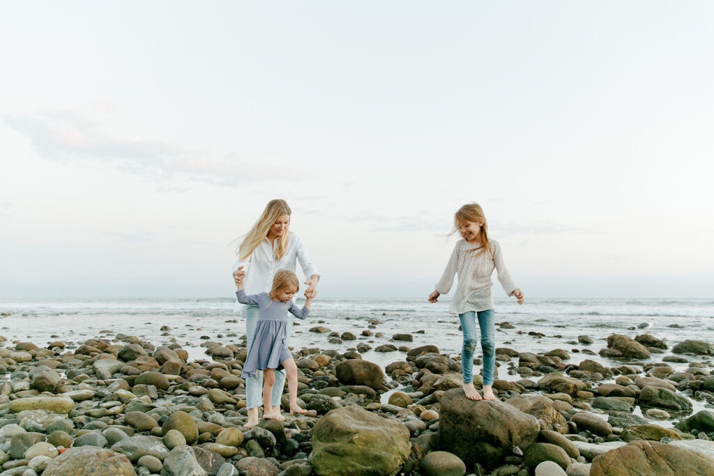 mom and 2 daughters walking in tide pools a the beach