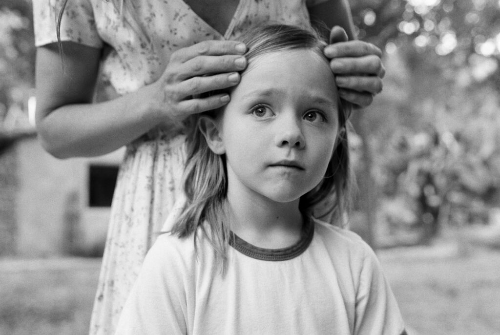 black and white photo of young boy with a pensive look as mother lovingly touches hair
