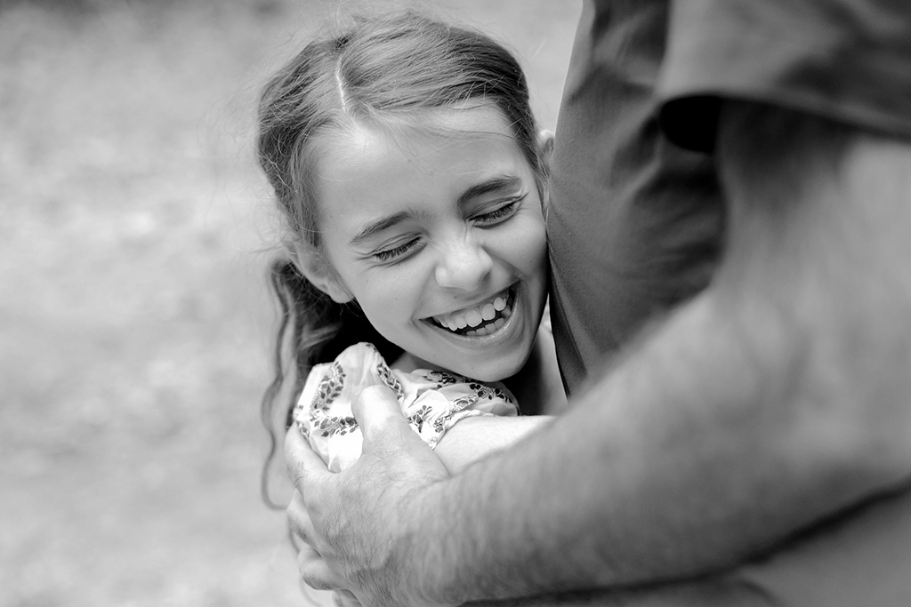 black and white photo of girl hugging dad, close up with eyes closed