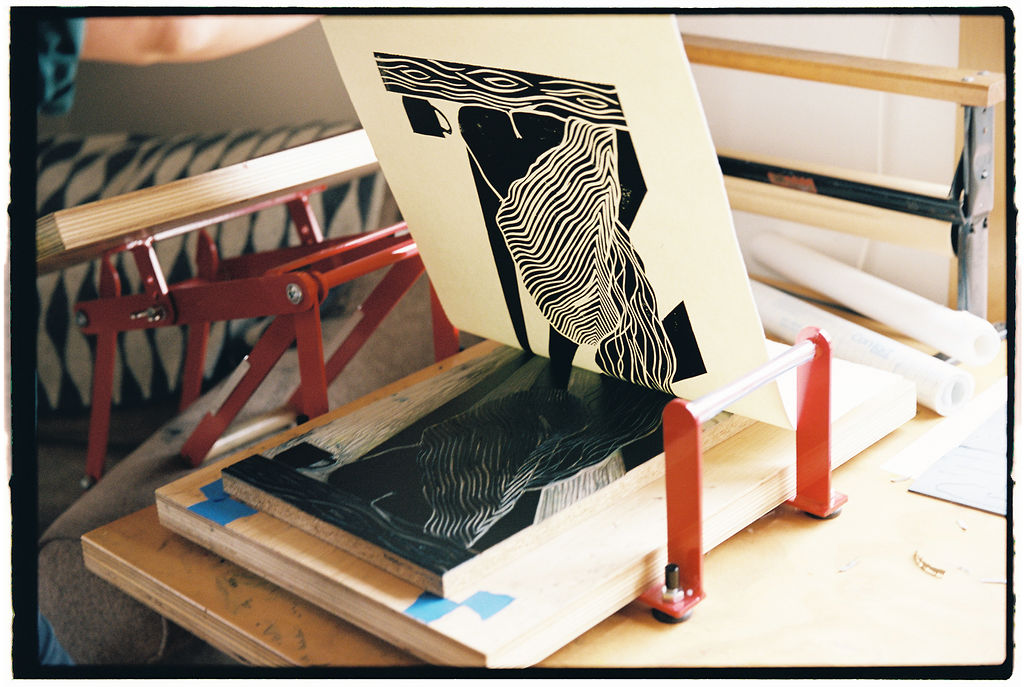 A woman is making a print on a table.