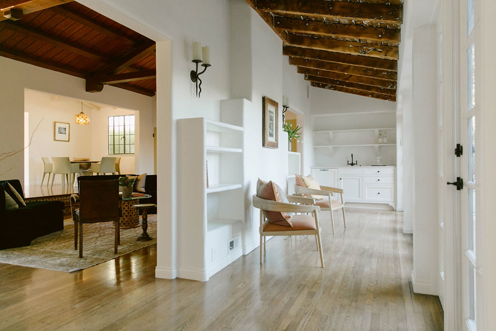 Modern living space with open floor plan, featuring exposed wooden beams and minimalist decor.