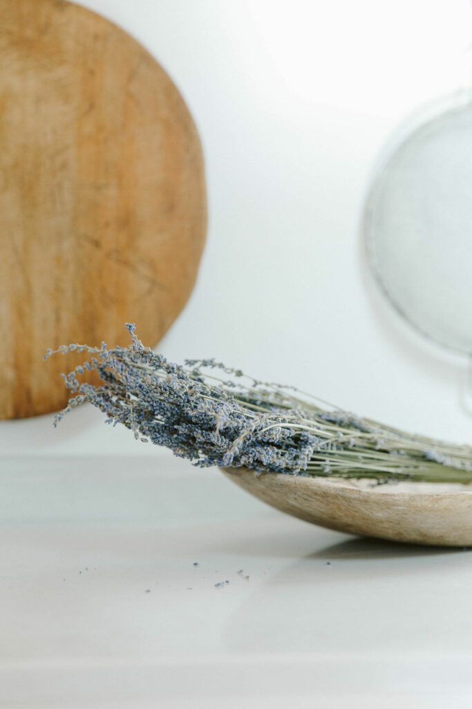 Bunch of dried lavender on a wooden surface with kitchen utensils in the background.