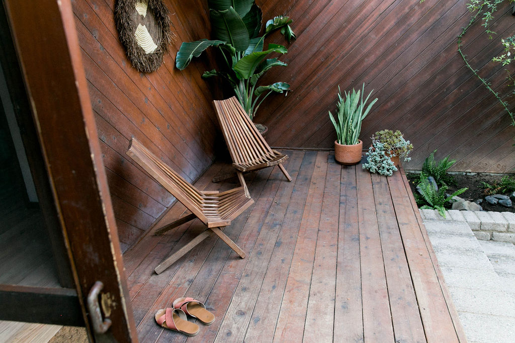 Wooden patio with a modern chair and potted plants.