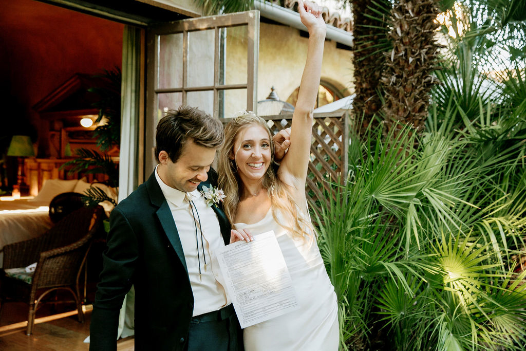 Bride and groom celebrating with marriage certificate in hand.