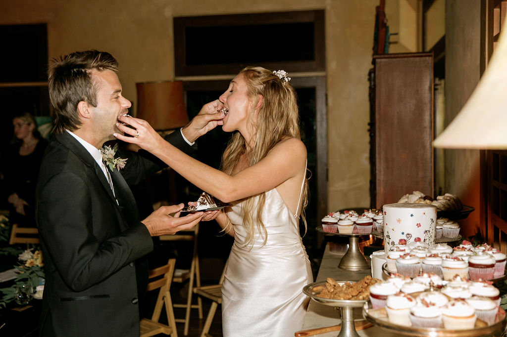 Bride and groom feeding each other cake at a wedding reception.