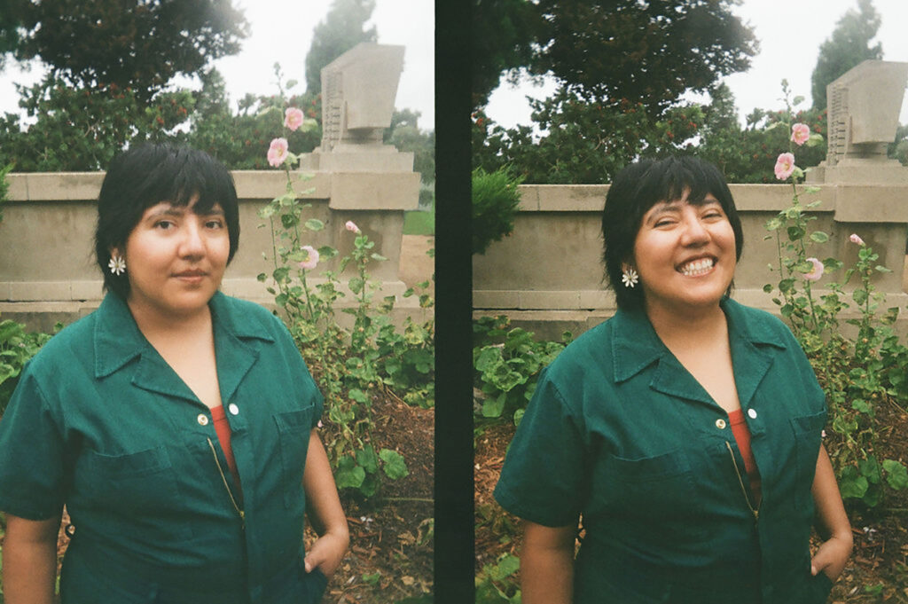 Diptych of a person in a green shirt, first image with a neutral expression, second image smiling, standing in front of greenery and flowers.